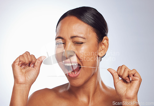 Image of Dental flossing, portrait or mature woman cleaning teeth for beauty or wellness in studio on white background. Wink, self care or healthy senior female model grooming her tooth or mouth for hygiene