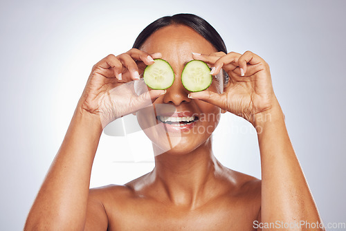 Image of Cucumber, face and natural beauty of happy woman in studio, white background and healthy diet. Female model, skincare and fruits on eyes for sustainable cosmetics, aesthetic dermatology and nutrition