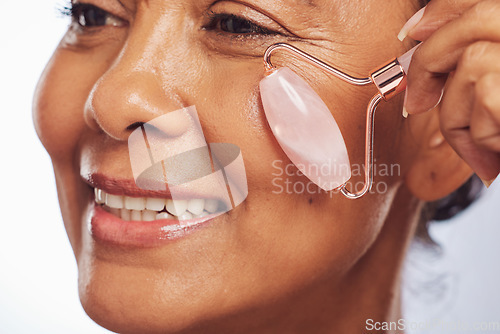 Image of Woman, face roller and massage for skincare, detox dermatology and aesthetic wellness in studio. Closeup of happy mature person, crystal stone tools and facial beauty cosmetics for lymphatic drainage