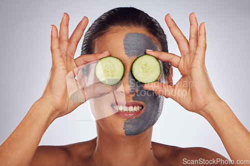 Image of Face, cucumber and mask with a model woman in studio on a gray background for an antiaging facial treatment. Eyes, skincare and fruit with a young female person using cosmetic lay on her face