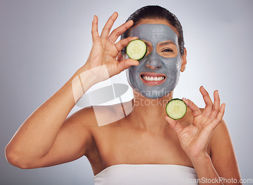 Image of Portrait, cucumber and mask with a model woman in studio on a gray background for an antiaging facial treatment. Beauty, skincare and fruit with a young female person using cosmetic lay on her face