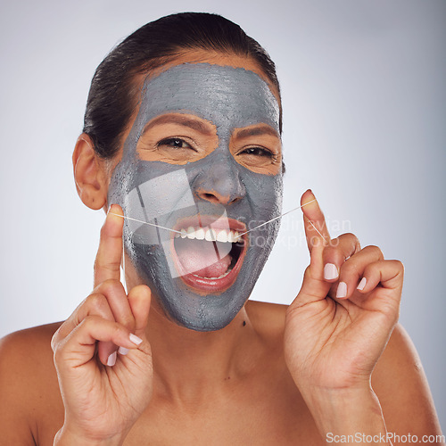 Image of Beauty, face mask and a woman flossing teeth for skincare, dental hygiene and wellness. Happy, portrait and a model or girl with gear for tooth cleaning and a facial isolated on a studio background