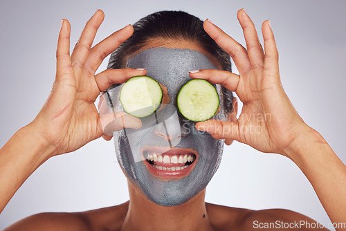 Image of Facial, cucumber and mask with a model woman in studio on a gray background for an antiaging face treatment. Eyes, skincare and food with a happy young female person using cosmetic clay on her face