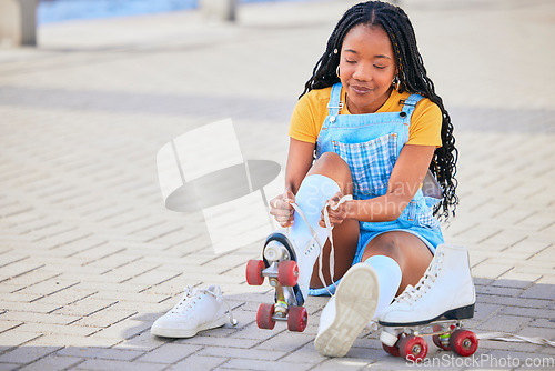Image of Roller skating, tie and safety with a black woman by the sea, on the promenade for training or recreation. Beach, sports and a young female teenager tying skates on the coast by the ocean or water