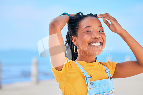 Image of Portrait, smile and hair with a black woman on a blurred background by the ocean during summer vacation. Face, happy and braids with a young female person outdoor on the promenade for a holiday