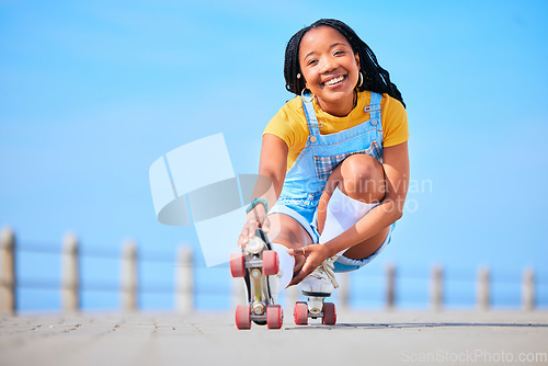 Image of Portrait, roller skating and balance with a black woman by the sea, on the promenade for training or recreation. Beach, sport and smile with a happy young teenager in skates on the coast by the ocean