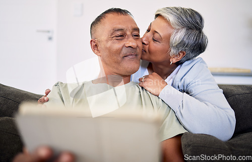 Image of Marriage, kiss and senior man or woman on sofa for retirement or quality time in home. Couple, hug and elderly man or woman with tech in living room for bonding together with internet on couch.