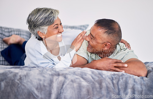 Image of Love, conversation and mature couple on their bed while relaxing, bonding and spending time together. Happy, smile and senior man and woman in retirement resting, talking and lying in bedroom at home
