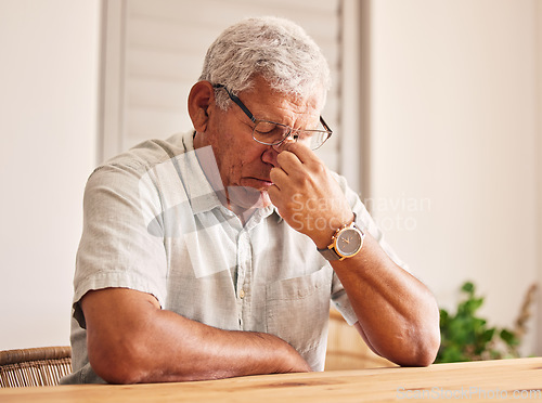 Image of Stress, headache and old man at table in home with glasses, worry and fatigue in retirement. Debt, anxiety and tired, frustrated senior person with mental health problem or crisis, exhausted and sad.