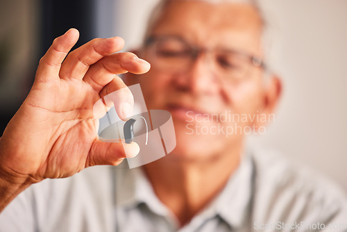 Image of Hand holding hearing aid, senior man and tech for ears, health and wellness for retirement in nursing home. Elderly person with disability, audio or sound technology to listen in closeup at house