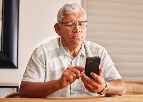 Image of Phone, social media and a senior man in his home, reading or typing a text message for communication. Mobile, contact and chatting with an elderly male pensioner sitting in his house for networking