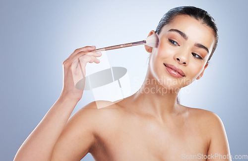 Image of Beauty, cosmetic and woman with a makeup brush in a studio for natural, glamour and face routine. Glow, self care and young female model with a cosmetology facial tool isolated by a gray background.