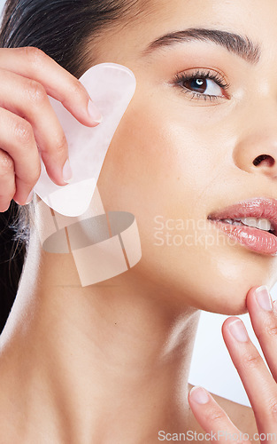 Image of Gua sha, skincare and asian woman portrait in studio for anti aging, cosmetic or facial massage on grey background. Rose quartz, face and lady wellness model with luxury, beauty or lymphatic drainage