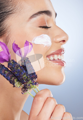 Image of Woman, face with cream and skincare with flower, natural beauty product with lavender or facial cosmetics in studio background. Skin care, moisturiser and purple flowers for organic cosmetic wellness