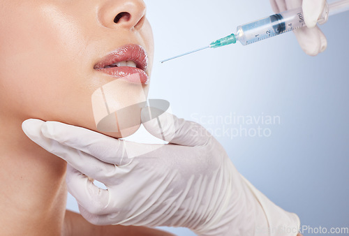 Image of Mouth, botox and plastic surgery with hands on the face of a woman for cosmetic surgery in studio on a blue background. Lips, filler or beauty and a female patient with her doctor for an injection