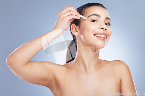 Image of Portrait of a woman plucking her eyebrows in a studio for grooming or hair removal face routine. Skincare, beauty and female model doing a facial epilation treatment with tweezers by gray background.