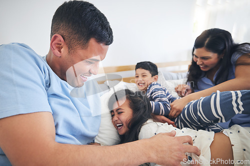 Image of Family, tickle and play on bed with fun and smile in a home with bonding and parent care. Happy, house and bedroom with a father, mom and children together in the morning with dad, mother and kid