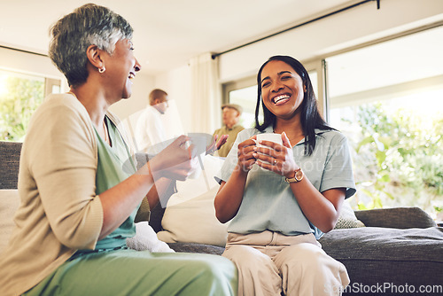 Image of Woman drinking a cup of coffee with her senior mother while laughing, talking and bonding at home. Happy, smile and elderly female person enjoying a cappuccino with her adult daughter in living room.