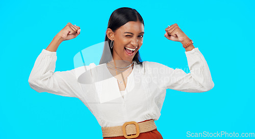 Image of Business woman, arm flex and happy face of a Indian female feeling power, succes and win. Work victory, champion and confident young employee in a studio with isolated blue background and a smile