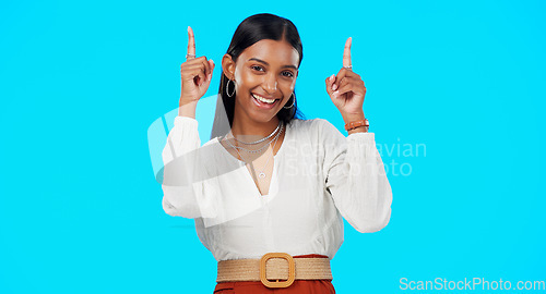 Image of Excited, happy and woman pointing up at mockup showing deal, sale and branding isolated in a studio blue background. Smile, fashion and portrait of Indian female show product placement or logo