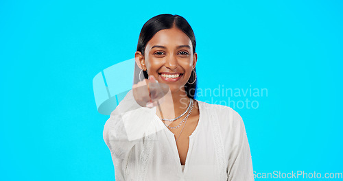 Image of Face, motivation and Indian woman pointing to you, promotion and happiness against a blue studio background. Portrait, female and lady with inspiration, choice and decision with selection and choice