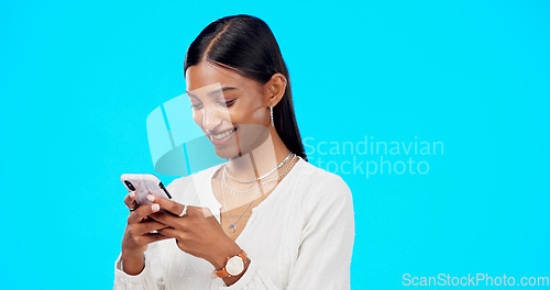 Image of Phone, typing and young woman isolated on blue background for social media post, networking and chat tech. Happy indian person or online user with mobile app, smartphone or cellphone in studio mockup