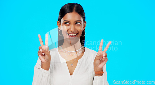 Image of Happy woman, peace and face wink in studio, blue background and color backdrop. Portrait of female model, v sign and winking of cool girl for victory, smile and fun mood for happiness, emoji or hands