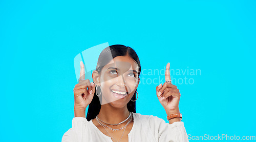 Image of Mockup, face and Indian woman pointing up, promotion and success on a blue studio background. Portrait, female and lady with gesture for motivation, inspiration and carefree with decision and choice