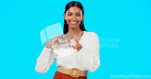 Image of Happy woman, heart hands and face in studio, blue background and backdrop of care, kindness or emoji. Portrait, female model and finger shape of love, thank you and smile of trust, peace or hope icon