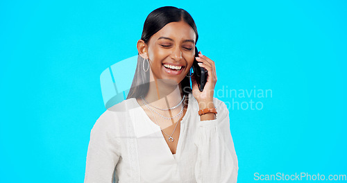 Image of Happy phone call, business woman and studio with a Indian female talking and speaking. Mobile communication, online discussion and networking of a young person smile with isolated blue background