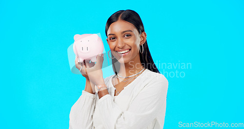 Image of Piggy bank, happy face and Indian woman with a smile from savings, investment and finance. Isolated, blue background and portrait of a young female with happiness from cash saving and safe budget