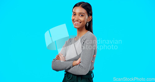 Image of Face, smile and business woman with arms crossed in studio isolated on a blue background. Boss, professional and happy, funny and confident female entrepreneur from India with pride for career or job