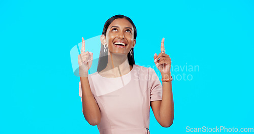 Image of Face, pointing and Indian woman with direction, motivation and cheerful against a blue studio background. Portrait, female and lady with gesture for choice, direction and brand development with smile