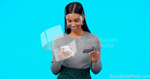 Image of Online shopping, phone or girl with credit card in studio for payment via internet website or fintech. Happy smile, blue background or Indian woman typing money transfer via digital mobile banking