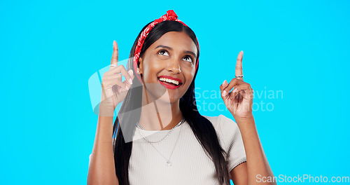 Image of Face, motivation and Indian woman with decision, pointing and wellness against a blue studio background. Portrait, female and lady with smile, direction and choice with inspiration, promotion and joy