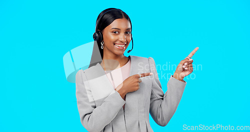 Image of Call center, portrait or happy woman in studio pointing for promotion or product placement on blue background. Smile, mockup space or Indian girl in headset at technical support or customer services