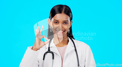 Image of OK hand and woman doctor isolated on blue background for healthcare success and service support. Like, yes and agreement sign or emoji of Indian person or medical worker face or portrait in studio