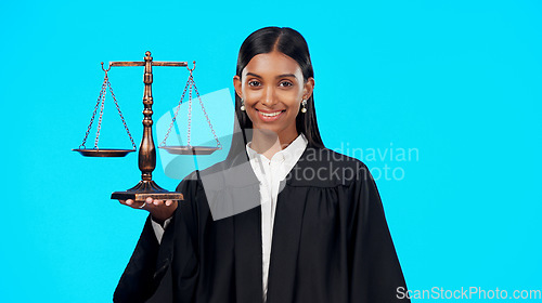 Image of Portrait, balance scale or happy woman lawyer in studio for justice system, career services or marketing. Fair legal worker, mockup space or trusted Indian girl attorney with smile on blue background