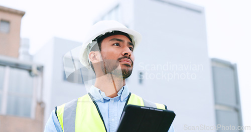 Image of Construction worker holding a digital tablet while doing inspection. Organized male engineer or technician in a hardhat checking project plan with latest tech. Worker looking or overseeing operations