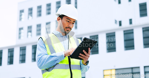 Image of Male engineer checking data on digital tablet and inspecting construction site. Technician in a hardhat doing management and project planning outdoors. Skilled worker looking or overseeing operations