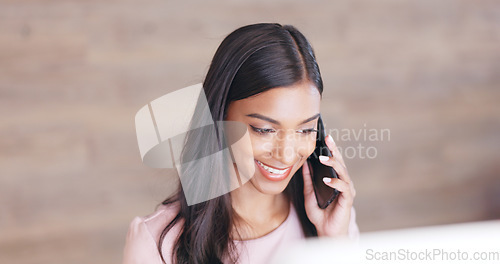 Image of Secretary talking on a phone while working on a computer at a front desk. Cheerful young receptionist with a friendly tone scheduling appointments and confirming meetings with clients in an office