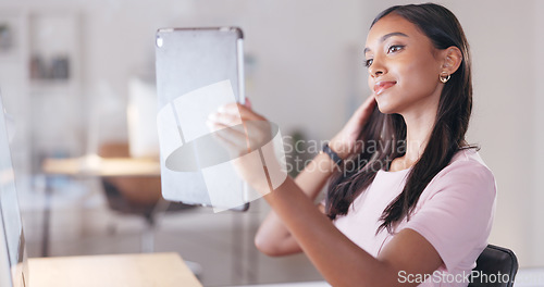 Image of Young happy woman taking a selfie with a digital tablet while relaxing in an office at work. One smiling female student taking pictures to post on social media while sitting alone in a library