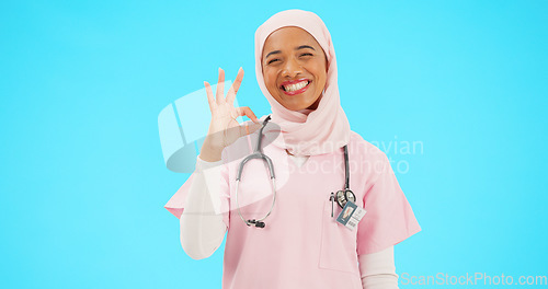 Image of Face, nurse and Muslim woman with ok sign in studio isolated on blue background mockup. Smile, portrait and happy medical professional or Islamic person with okay emoji, hand gesture, like or success