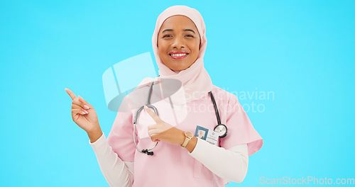 Image of Woman doctor pointing to mockup isolated on blue background for healthcare presentation or product placement space. Happy face of nurse or medical muslim person show advertising mock up in studio