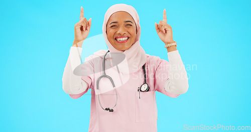 Image of Muslim nurse, happy woman and pointing finger portrait with space for healthcare, religion or happiness. Islamic female medical worker with hand, smile and hijab for announcement on blue background