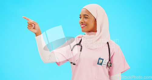 Image of Face, nurse and Muslim woman pointing to mockup in studio isolated on a blue background. Portrait, healthcare professional and happy Islamic person with marketing, advertising or product placement.