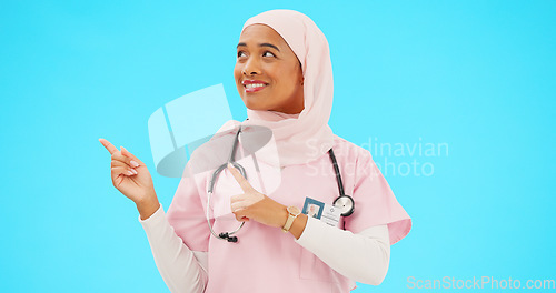 Image of Woman doctor pointing to mockup isolated on blue background for healthcare presentation or product placement space. Happy face of nurse or medical muslim person show advertising mock up in studio