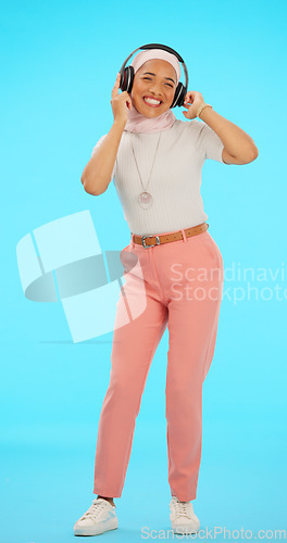 Image of Headphones, dance and Muslim woman in studio on blue background listening to music, song and audio. Dancing, party mockup and isolated female on chromakey streaming radio for peace, relax and happy