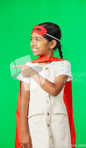 Image of Face, superhero costume and girl pointing on green screen in studio isolated on a background. Smile, cosplay character and happy child or kid in cape point to mockup, product placement or marketing.