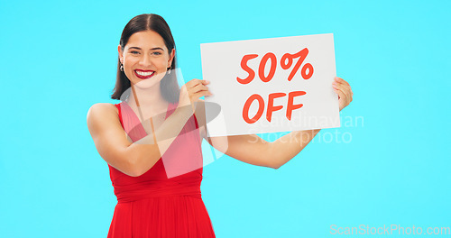 Image of Sale sign, portrait and woman in studio advertising percentage or discount rate on paper or banner. Smile of a happy female on a blue background for fashion promotion deal, savings or deal and offer